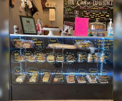 Display case filled with various baked goods, including breads and cookies, with colorful labels and prices.