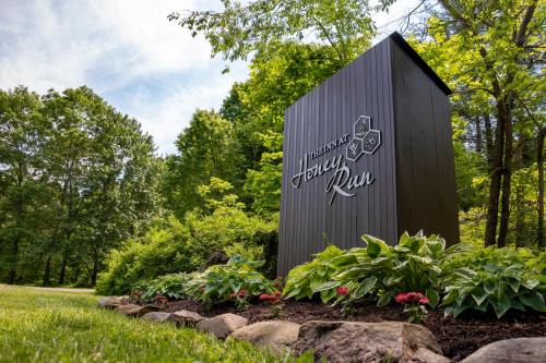 Sign for Honey Run surrounded by greenery and flowers, set in a lush, natural landscape.