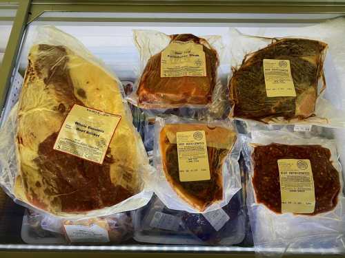 Various cuts of packaged meat with labels, displayed in a freezer case.