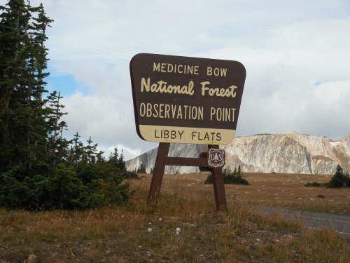 Sign for Medicine Bow National Forest, indicating Observation Point at Libby Flats, with mountains in the background.