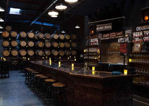 A dimly lit bar with wooden stools, a long counter, and barrels in the background, featuring candles on the tables.