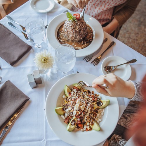 A top-down view of two plates: one with a dessert and the other with a fruit dish, both elegantly presented on a table.