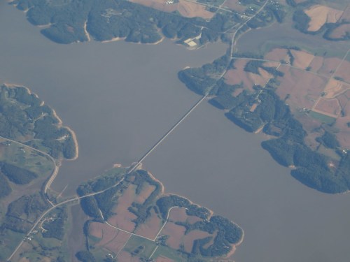 Aerial view of a river with islands and a bridge connecting land on either side, surrounded by farmland.