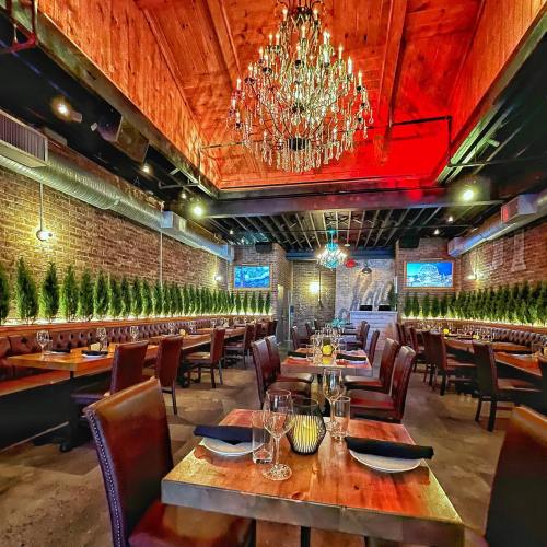 Cozy restaurant interior with wooden beams, a chandelier, and elegant seating along a brick wall.