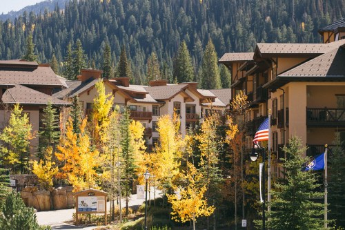 A scenic view of a mountain resort surrounded by autumn trees and a clear blue sky.