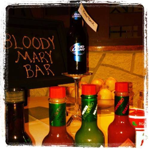 A display of a Bloody Mary bar featuring various hot sauces and a Bud Light beer bottle.