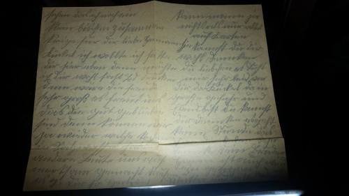 A close-up of an old, handwritten letter on yellowed paper with faded ink and cursive writing.
