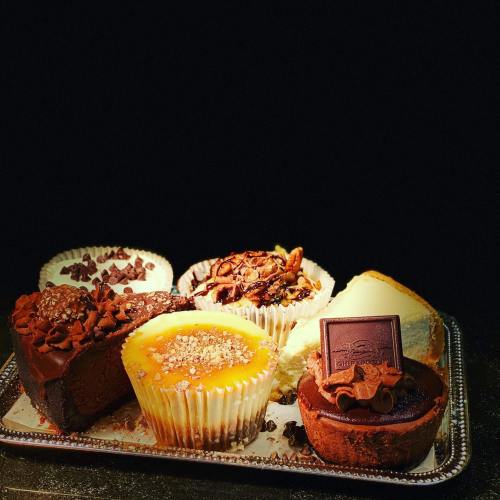 A variety of desserts including chocolate cake, cupcakes, and a creamy dessert, arranged on a silver tray.