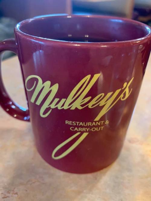 A maroon coffee mug with the text "Mulkey's Restaurant & Carry-Out" in gold lettering.