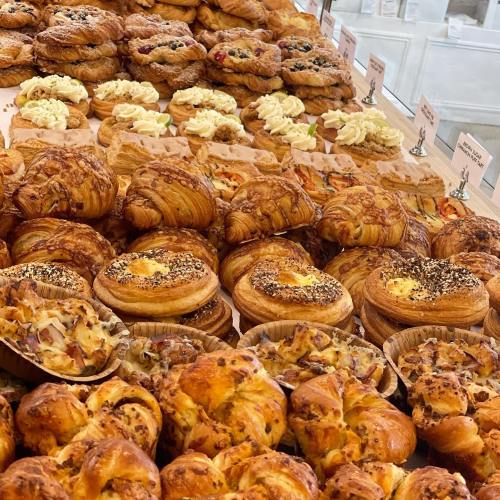 A variety of freshly baked pastries, including croissants and sweet rolls, displayed on a wooden table.