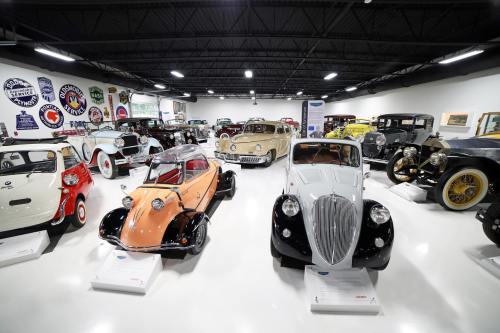 A collection of vintage cars displayed in a museum, featuring various models and colors in a well-lit space.