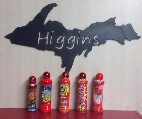 Colorful novelty poppers lined up in front of a black silhouette of Michigan, labeled "Higgins."