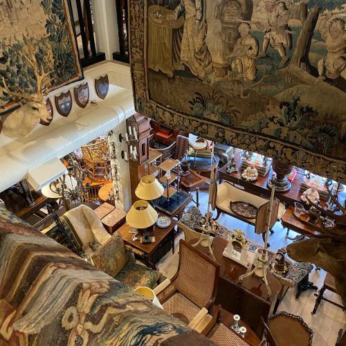 A cozy antique shop filled with vintage furniture, tapestries, and decorative items, creating a warm, inviting atmosphere.