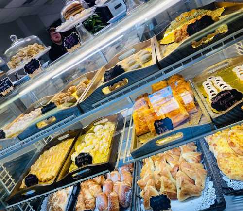 A display case filled with various pastries and baked goods, including croissants, tarts, and cookies.