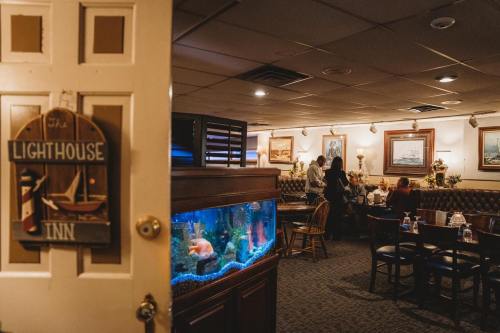 A cozy restaurant interior featuring a lighthouse sign, an aquarium, and patrons dining at tables.