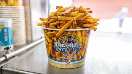 A large cup filled with golden, crispy French fries from Thrasher's, labeled "The original French fries since 1929."