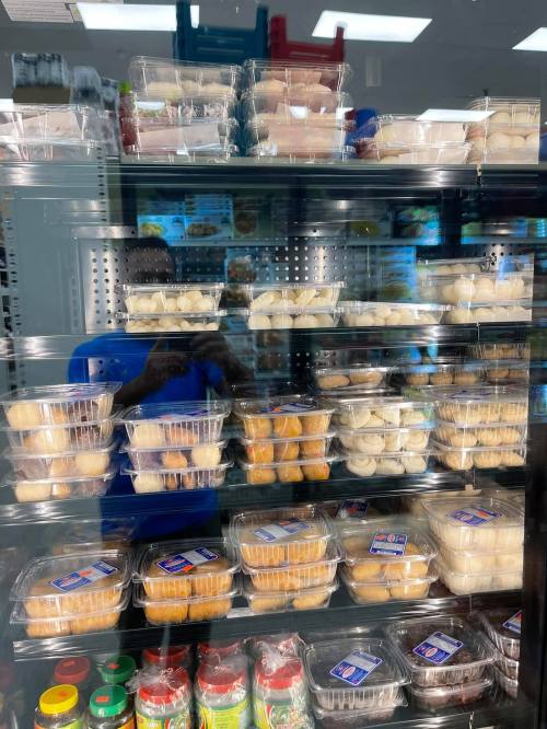 A display case filled with various packaged desserts, including cupcakes and pastries, in a store.