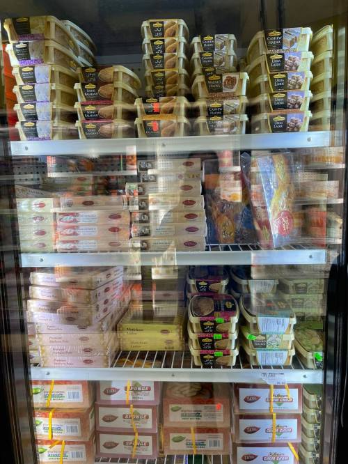 A freezer display filled with various packaged frozen foods, including trays and boxes of different products.
