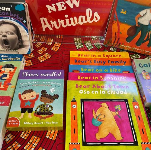 A colorful display of children's books with a "New Arrivals" sign, featuring titles about bears and mindfulness.