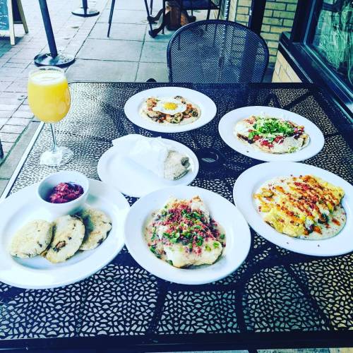 A table set outdoors with a variety of colorful dishes and a glass of mimosa.