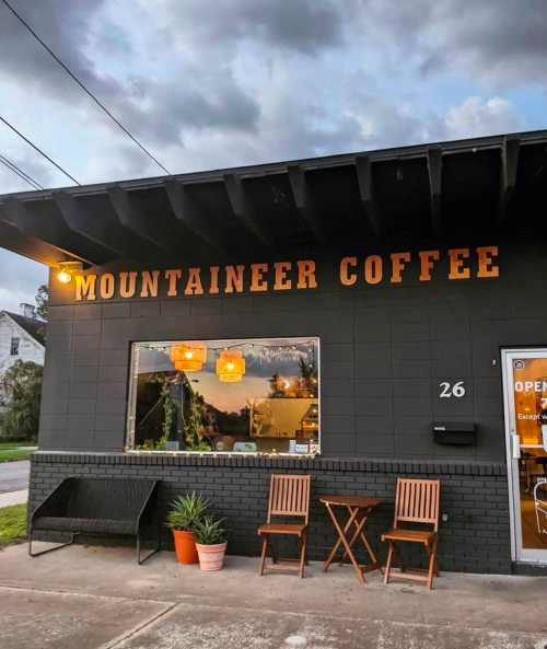 Exterior of Mountaineer Coffee shop with a sign, window displays, and outdoor seating.