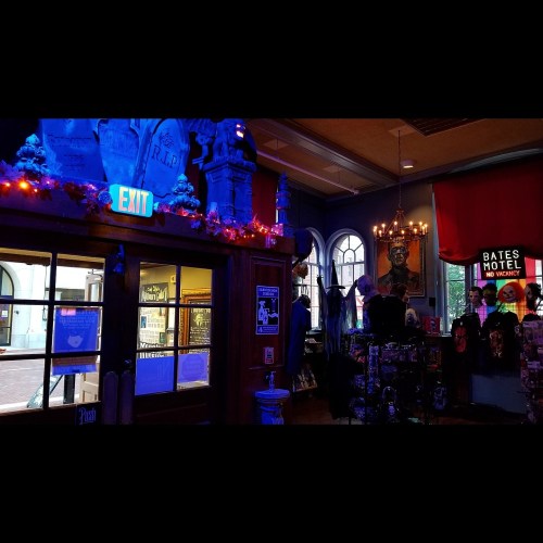 A dimly lit room with colorful lights, featuring an exit sign, decorations, and a "Bates Motel" sign.