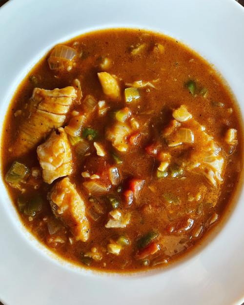 A bowl of hearty fish stew with chunks of fish, vegetables, and a rich, flavorful broth.