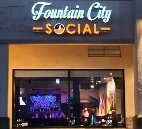 Exterior view of Fountain City Social, featuring a colorful sign and a glimpse of the vibrant interior.