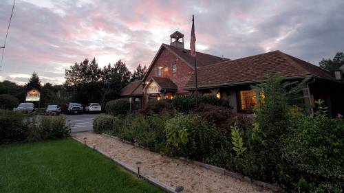 A charming building with a sloped roof, surrounded by greenery, under a colorful sunset sky.