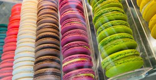 A colorful display of macarons in various flavors, arranged in neat rows.