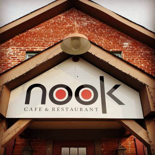Sign for "nook Cafe & Restaurant" on a brick building with a triangular roof.
