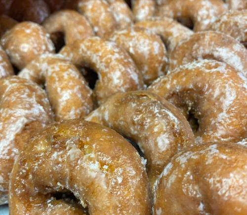 A close-up of freshly made, powdered sugar-coated donuts arranged in a pile.