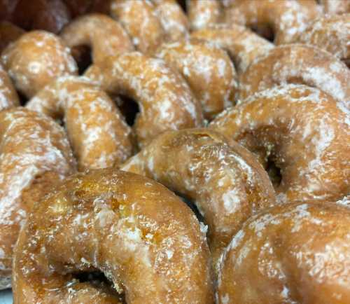 A close-up of freshly made, powdered sugar-coated donuts arranged in a pile.