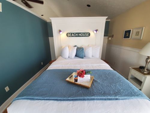 Cozy bedroom with a beach house theme, featuring a large bed, decorative pillows, and a tray with flowers.
