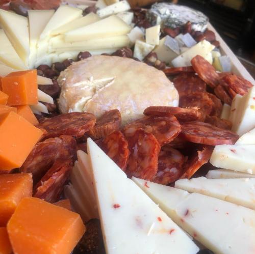 A colorful cheese platter featuring various cheeses, cured meats, and nuts arranged artfully.
