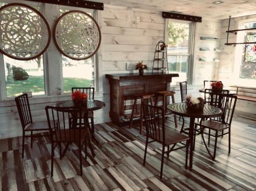 Cozy interior with wooden tables and chairs, decorative wall art, and large windows letting in natural light.