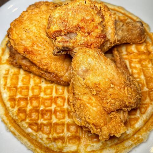 Fried chicken pieces served on a golden waffle, creating a delicious comfort food combination.