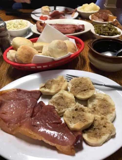 A table spread with various dishes, including ham, biscuits, green beans, and mashed potatoes.