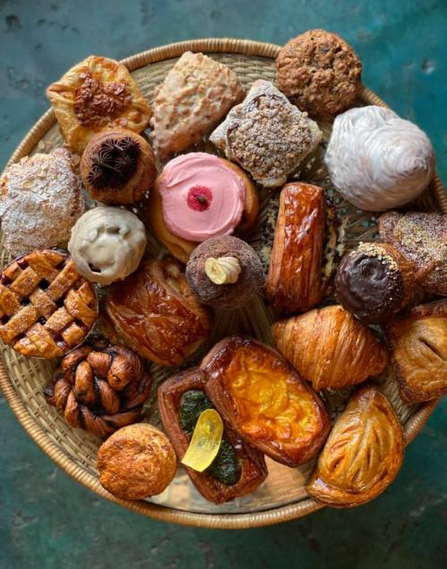 A variety of baked goods arranged in a woven basket, including pastries, cookies, and sweet treats.