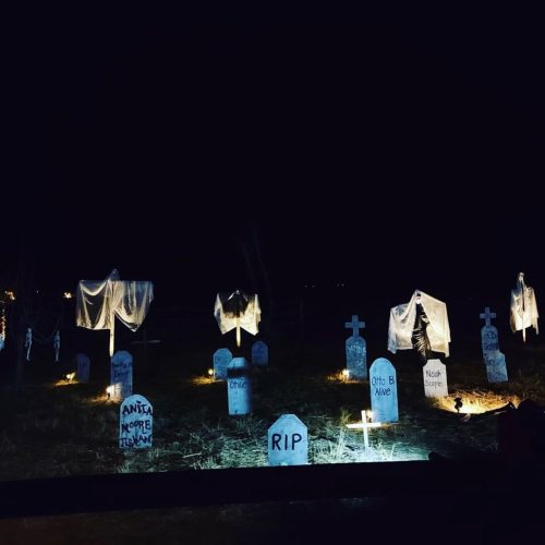 A dimly lit graveyard at night, featuring tombstones and ghostly figures draped in white cloth.