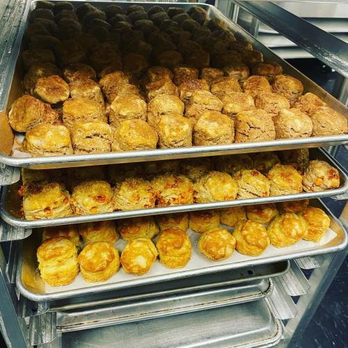 Trays of freshly baked biscuits stacked in a commercial kitchen, showcasing a variety of golden-brown textures.