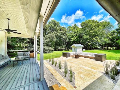 A spacious outdoor patio with seating, surrounded by greenery and a blue sky with clouds.
