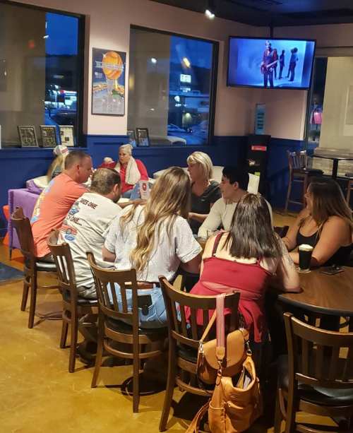 A group of people sitting around a table in a casual dining setting, engaged in conversation.