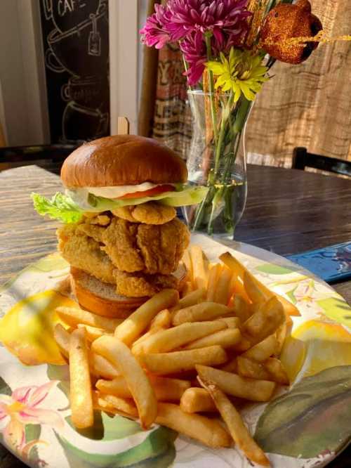 A crispy chicken sandwich stacked with lettuce, tomato, and pickles, served with a side of golden fries.