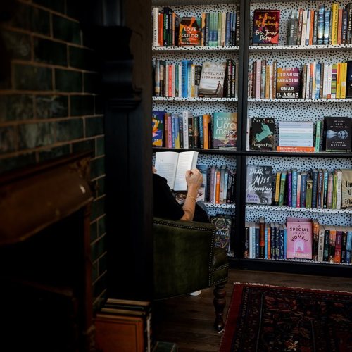 A person reading a book in a cozy nook surrounded by shelves filled with colorful books.