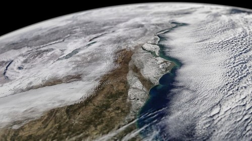 Aerial view of the East Coast of the United States, showcasing land, water, and cloud patterns from space.