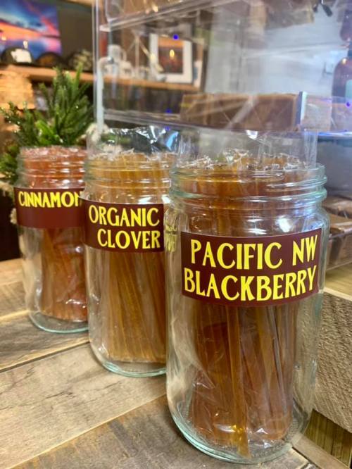 Three jars filled with honey sticks labeled "Cinnamon," "Organic Clover," and "Pacific NW Blackberry."
