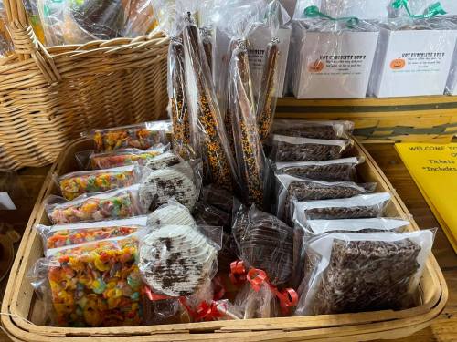 A basket filled with assorted wrapped treats, including chocolate-covered snacks and colorful candy clusters.