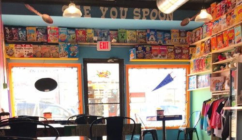 Colorful cereal-themed café interior with shelves of cereal boxes and a bright, inviting atmosphere.