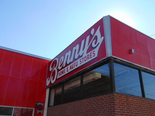 Sign for Benny's Home & Auto Stores on a red building, featuring large white lettering against a bright blue sky.